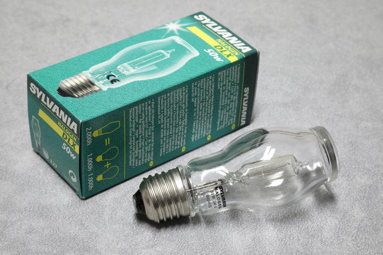 Sylvania 50w DLX Hard Glass Halogen Capsule: Clear
1 x Sylvania 50w DLX double-jacketed tungsten halogen lamp with an aluminosilicate hard glass capsule instead of the more usual quartz which is quite unusual for a European lamp.

The advantages of a hard glass capsule is that it is cheaper and easier to work with as it's melting point is a lot lower than quartz.

The disadvantages are that they can blowup quite energetically when they reach end of life which has to be taken into account.
In this case protection is provided in the form of a very impressively thick and heavy outer envelope which is quite something when you have the lamp in your hand!
In fact the outer envelope was made by a Belgian manufacturer of perfume bottles and you can really see the lineage!
