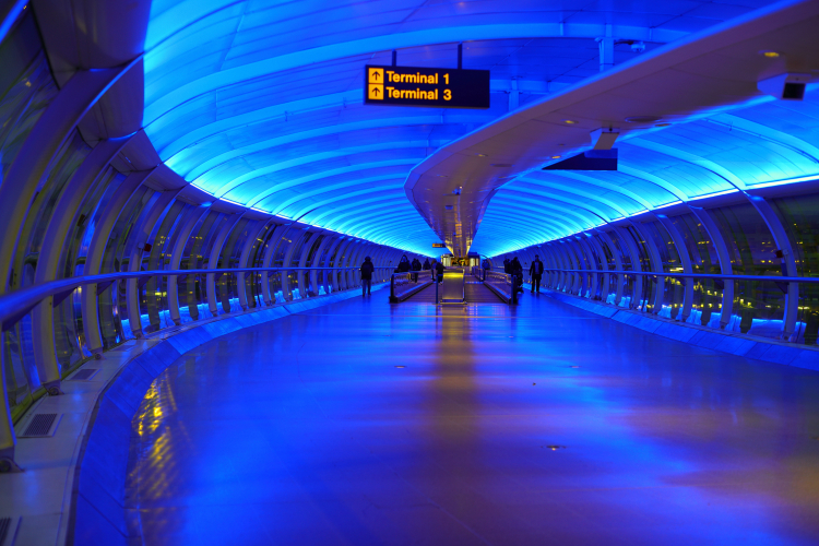 I'm Blue...
 ...Da-ba-dee, da-ba-da.

The walkways connecting the carparks and railway stations with the passenger terminals of Manchester Ringway International airport is lit with blue lighting.
It's been like this for decades so no idea what it was originally, be it neon or coloured fluorescent.
Probably LED now though
