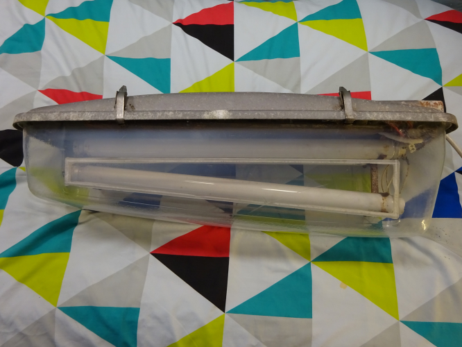 GEC Z8256
Recently acquired into the collection is this incredibly special, and as far as is known one off GEC Z8256 (not to be confused with the Z8526 – That's a 250w/400w MBF/SON Turtle) fluorescent lantern to survive in a collection. The reason I say ‘one off’ is because its a Blackpool special.

Typically these lanterns are seen with two 40w 2’ tubes, indeed all other examples I’ve seen have this lamp configuration. However this special variant takes four 20w 2’ tubes. The idea is that after midnight, two tubes would switch off allowing dimming through the rest of the night, likely till around half five in the morning.

I bought it from a collector who had rescued it originally in the 80’s, who then simply placed it in his garage and left it untouched until I hosted a lighting meet, and he bought it along. We decided it need to be lit, and having put some wire to it, the lantern shrugged off the disuse and sprang into life after 40 years of not having any power to it. Beat that LED! He then exclaimed he might be looking to sell it, and after I made an offer, he accepted and here we are now.

The lantern features a rather well proportioned wedge shape bowl, and considering the lower tubes follow the bowls profile, I imagine it done an impeccable job of lighting the road. The bowl is sadly cracked and broken, but what goes for it is how clear it is, its incredibly well preserved all things considered. I carefully glued all the cracks and splits back together, and then wet dry sanded the edges to try and hide the damage as much as possible. Its not completely gone, but its a massive improvement, restoring some rigidity back to the fragile bowl. One large hole is yet to be filled in, however I’ve sourced a wrecked Alpha 9 with a perfect matching area in which I can cut off and fit to this bowl.

The gear inside is immaculate, which is shocking considering where it was once installed, Blackpool quite frequently has salty sea mist blowing over, its why I call it the lantern destroyer town. No doubt only seeing 20 years service is the reason why its survived as well as it has.

So now for restoration, this will see a full restoration as per usual, and then its ready for decades more service.
