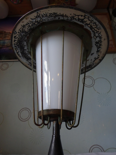 Falks GLS Pedestal light, before restoration.
I bought this beautiful Falks Pedestal light from an antiques flea fair I frequently visit in May, mounted on a very oversized and blocky wooden base that really doesn't match with the light well. The finials been replaced with an absolutely hideous lifting eye, and the three ball nuts on the canopy have also been replaced with normal hex nuts too, meaning its a nuisance to get into. Speaking with the seller, he wanted to bring its 'industrial' looks out, which imo is the wrong way to go about this, its more of a decorative functional light to my eyes.

Seeing past that, I knew the construction of the light is pretty much nothing but brass, and the cone surprisingly is glass. Knowing how well these clean up, I took a punt and bought it despite the nightmare I knew I'll have finding a replacement finial, especially since I don't even know what it looks like or even its dimensions. I gave it a quick power up not long after I got it home, and it really is a stunning looking light when lit.

After that, I immediately removed it from the wooden base, got that horrific lifting hook off and binned it, and then replaced the hex nuts back to the correct ball nuts. I could only get them in M4 thread, and since the originals are 4BA, that meant I had to drill upwards to 3/16 BSW, thread lock them in, cut them flush and drill and tap to the correct thread. 

Admittedly I'm a bit stuck regarding a new finial, ideally I need to find someone who has an example of these. The restoration will involve stripping all the paint off, before painting the underside of the canopy white, and then I'll simply polish and lacquer everything else to bring out the natural beauty of the brass. The base will be retained, but will be given to someone to turn the wood to a more appropriate shape, before staining it with a light coloured wax to compliment the brass. Whether I end up installing it outdoors though is another thing, it really is too nice to put outdoors again imo.
