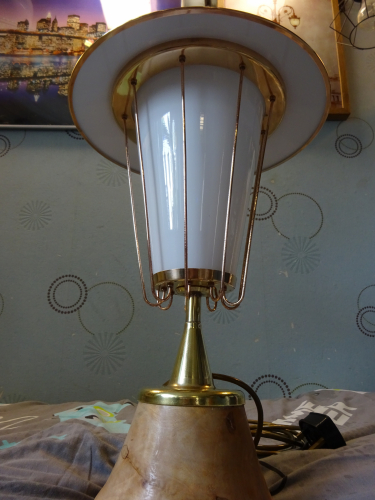 Falks GLS Pedestal light, after restoration.
Earlier this year I bought in this gorgeous Falks Pedestal light, which had been crudely 'upcycled' into a table lamp. Seeing past the mess to the potential it hid beneath the paint and dirt, I bought it and begun looking around for the parts that had been replaced or was missing.
 
First up was replacing the three hex nuts that should have been ball nuts. I managed to find some on eBay in an M4 thread, however they needed to be 4BA thread. I drilled the original thread out, retapped to M5, threadlocked the brass bolt in place, cut it flush and then drilled and tapped to 4BA. Part one done, the next and more complicated part was to find an original finial.

For this I needed to find a photo of one, and thanks to a fellow collector, was show an image of how it should look. This left me needing a piece of brass to turn and reshape, and that ended up showing itself in the most unusual of circumstances. Whilst digging around a column to move it while at work, a team mate hit some metal. It turned out to be an old brass lever, but with the almost perfect dimensions to become a new finial. I got it home, cut most of the bar off to allow me to put it in a drill. I cable tied the drill so it'd constantly spin, and with Dads help and his trusty flap disc in the angle grinder, turned the lever till it matched what I needed. I then cut the bar off completely before drilling and tapping into the now finial to 5/8" BSW. I got a brass bolt, washer and a rubber seal, and screwed the finial into place, really finishing off its 50's style beautifully. So that's the light completed again, the real restoration can now begin.

Polishing the light was actually fairly simple, the black paint on the base chipped off, and the 9 uprights were given to a neighbour to polish since he has a polishing wheel. Once the lid was polished, I painted the inside white, really smartening the whole thing up.
After much debating, I decided to keep it as a table lamp, its too nice to put outside again imo. So the wooden base was given to a mates stepfather, and he turned it with his lathe into a more fluted design, allowing the base of the pedestal to sit over the wood and not in it. It was finished with a light coloured wax to compliment the brass of the now fully polished light. Screwed back to the wood with 4 brass screws, the light was reassembled and rewired with gold flex, a much better fit than the black flex it was wired with.

Honestly I think this has turned out better than I thought it would, and the opal glass really softens the light from whatever lamps inside it (currently a CFL) so this may end up becoming my bedside table lamp.
