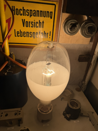 SELZ DRV 750 Soviet self ballasted mercury vapour lamp for greenhouses -- start up
mercury vapour lamps become fairly popular for the use in Greenhouses after they were launched and before HPS become popular, as well as in small domestic applications were growing HPS lamps were never made in small enough wattages. One example for the latter is the Osram HQL-R Delux 80W which can also be seen in this album. 
For industrial settings the 400W Lamp become popular. It was sealed in the slightly bigger 700W envelope to allow a better beam positioning and uniformity. These lamps would be mirrored or have a titan oxide reflector, which allowed cheap fittings and a new reflector with every lamp. The eliptic shape allowed a more compact lamp setup. The first lamp of that type that was commercially launched is the Philips HLRG which can also bee seen in this album. 

The soviet for them self did also copping this design of lamp with the ????400-1 lamp. eventually this lamp was also improved with an extra layer of phosphor. These lamps were vital because of the short growing seasons in some parts of the soviet union. 

However the soviet scarcity economy-fueled by communism- lead to problems providing ballast so this self ballasted lamp was developed. 
