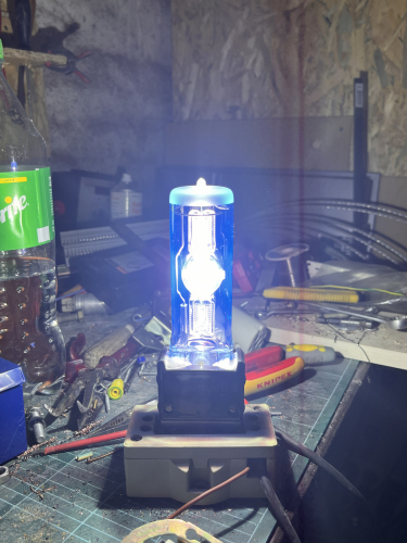 2015 Osram HMI Event 1200W Quartz metal halide lamp 
2015 1200W metal halide projector lamp for immediate hot restrique, compact fixtures and long life launched by Osram in 2015 for the Event industry. These lamps are basically a refined version of the standard HMI 1200W SE UVS. You can see the specially doped quartz envelope to block UV radiation is glowing blue.

The lamp is run on an ARRI 575/1200W electronic ballast with external ignitor. The square wave operation at 50Hz is rather loud and can become annoying with time. 
