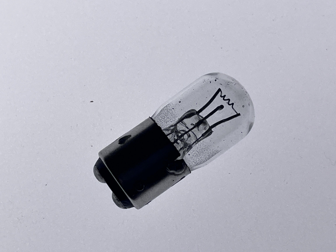 Thorn M1 Low voltage mercury UV source
Here you can see a miniature UV source for low voltage DC application. The lamp was originally developed by Siemens Brothers in the UK as a UV source to excite fluorescent colored panels for example in airplane.

Small UV sources that could be ballasted by standard resistors and be run on the 24V DC of commercial vehicle become interesting during World War II for all major lamp manufacturers.

Night flying over enemy territory at night made it necessary to illuminate aircraft cockpits in ways that made it difficult to see the same from ground or from combat air patrols. The use of normal GLS lamps can make aircraft easily notable against a dark background at night. The solution found was that instruments were marked with fluorescent paints and the cockpits would be lit by long wave UV lamps.

In order to easily be used in an airplane, the lamps needed to have an arc voltage lower then the board voltage and should be capable of running on DC. Both GE and Siemens developed a lamp functioning very similar to another, with the discrepancy of GE using a phosphor on its F5000 lamps while Siemens M1 lamp is clear.

In order to run on low voltage the lamp has a small arc length and low inner pressure. The cathode is a coiled coil tungsten filament with emissive powder which I believe to be very similar to fluorescent cathodes. The anode is a simple wire.
In order to start the lamp the filament is preheated via a a 33Ohm resistor at a maximal current of .95A. After becoming emissive a glow discharge forms between anode and cathode. The discharge current is limited to .8A by a 24Ohm resistor . In order to get the advertised lifespan of 200hrs out of the lamp, the filament heating needs to be disconnected in order to prevent cooking of the emitter.

After the War a second AC operated lamp the M2 was developed. This M1 lamp was continued to be manufactured for other special applications. First under Siemens and after its acquiring of the same under the Thorn name.
The lamps were used in scientific applications as reference for the mercury lines, in insect traps and as exciters for fluorescent materials, minerals and other materials.
To my knowledge these lamps only disappeared in Thorn’s catalogue in the early 1980s.
